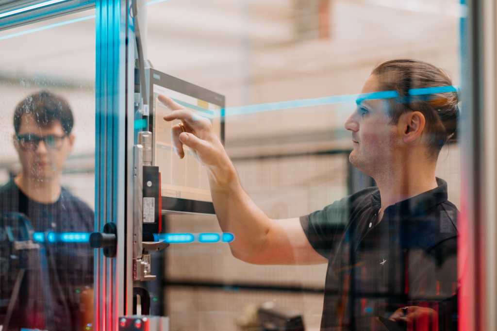 Paul Kempt, a la izquierda, programador de thyssenkrupp, y Marcus Schoenherr, ingeniero de thyssenkrupp, trabajan en la máquina de pruebas de células de baterías de vehículos eléctricos en la fábrica de thyssenkrupp en Chemnitz, Alemania.